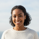 Portrait of a smiling young adult of color, looking confidently at the camera.