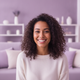 Headshot of a smiling woman in her late 20s, with a blurred living room background in dusty lilac and soft lavender.